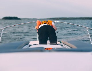 Person wearing a floating lifevest throwing up on a boat because of seasickness