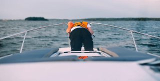 Person wearing a floating lifevest throwing up on a boat because of seasickness